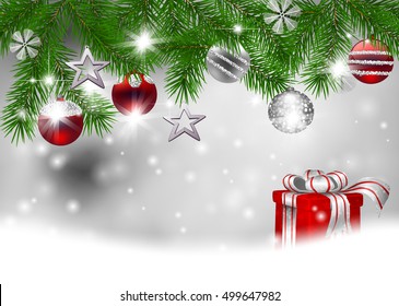 Fir branches decorated with Christmas baubles and gift on silver background with space for text.