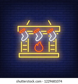 Fireplace with festive socks neon sign. Glowing chimney with gift socks on dark blue brick background. Can be used for winter, home decoration, Christmas