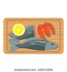 Fish salmon sliced on a kitchen board together with lemon on a wooden planks