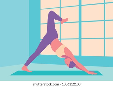 Fit woman doing yoga downward facing dog split pose in the workout studio