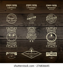 Fitness club badges logos and labels for any use, on wooden background texture