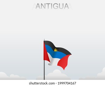The flag of Antigua flutters on a pole that stands tall under a white sky