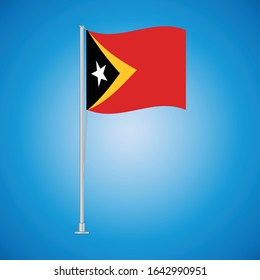 Flag of East Timor on a stand, developing in the wind, isolated on a blue background. Vector illustration eps 10.