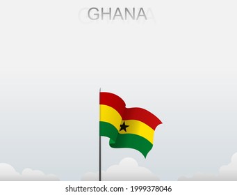 The flag of Ghana flutters on a pole that stands tall under a white sky