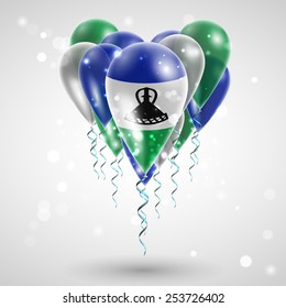 Flag of Lesotho on air balls in heart-shaped. Celebration and gifts. Ribbon in the colors are twisted under the balloon. Independence Day. Balloons on the feast of the national