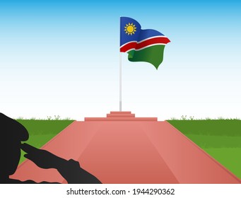 The flag of Namibia flew above the pole in the shadow of a soldier saluting the flag