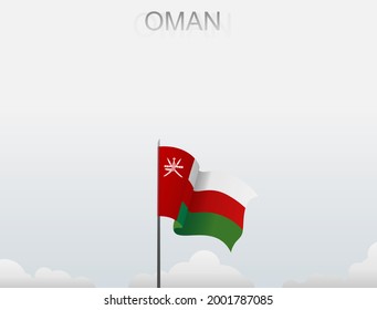 The flag of Oman flutters on a pole standing tall under a white sky