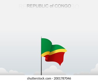 La bandera de la República del Congo ondea sobre un asta que se alza bajo un cielo blanco