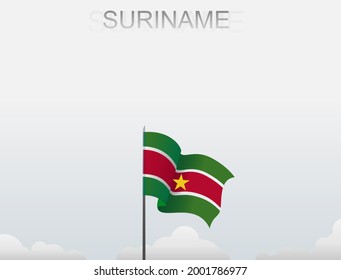 The flag of Suriname flies on a pole that stands tall under a white sky