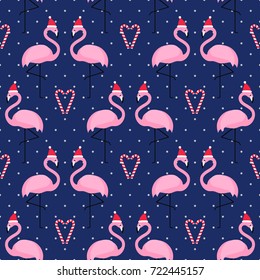 Flamingo in xmas hat with candy cane heart seamless pattern on blue polka dots background. Exotic New Year background. Christmas design for fabric, wallpaper, textile and decor.