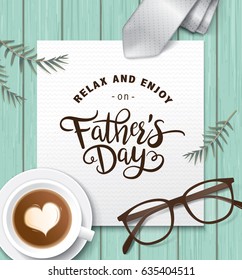 Flat lay style father`s day greeting card with cup of coffee, necktie and glasses on wooden table.