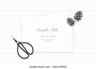 Flat lay top view elegant white composition paper pine cone and vintage metal scissors on wooden background.