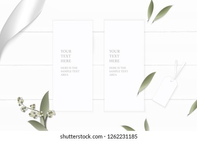 Flat lay top view elegant white composition paper flower leaf tag and silver ribbon on wooden background.