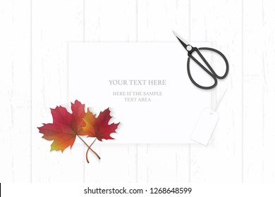 Flat lay top view elegant white composition paper autumn red maple leaf tag and vintage metal scissors on wooden background.