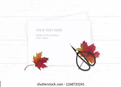 Flat lay top view elegant white composition paper autumn maple leaf and vintage metal scissors on wooden background.