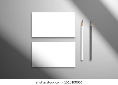 Flat lay with two blank white cards and pencils. Mocup for design with shadow from the window