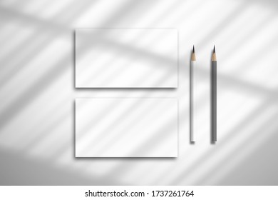 Flat lay with two blank white cards and pencils. Mockup for design with realistic shadow from the curtain