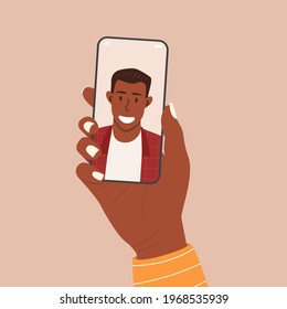 Flat vector cartoon illustration of a female hand holding a phone with an african-american man on the screen. An app for dating, video calls, and online conferences.