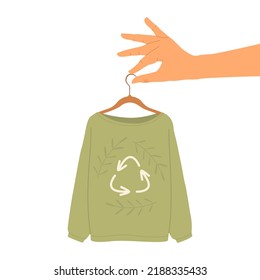 Flat vector illustration of a hand holding a hanger with a sweater made of recycled materials. Clothing with the symbol of waste recycling. Bio- and eco-clothing, eco-friendly textiles.