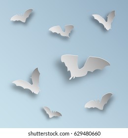 Flock of bats in paper art style on a light blue background. Flying bats silhouettes with shadows. Vector illustration