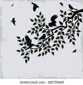 Flock of birds sits on branch of tree. Tree branch with leaves.