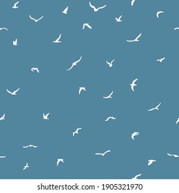 Flock of flying silhouette birds. Birds seamless pattern. White seagulls on a blue background. Vector illustration. 