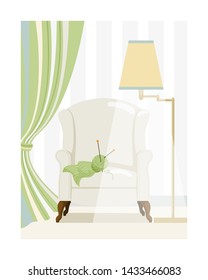 Floor lamp shines on the English armchair with a knitting, a ball, threads and knitting needles. Fragment of a room with a folded curtain and striped wallpaper
