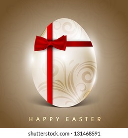 Floral decorated egg wrapped with red ribbon on brown background for Happy Easter.