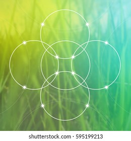 Flower of life - the interlocking circles ancient symbol in front of blurry photo of green bright grass. Sacred geometry - mathematics and spirituality in nature.