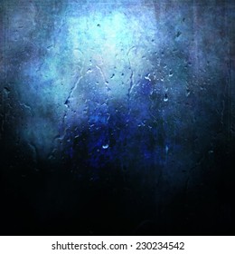 Flowing rain drops on fuzzy big textured blue spot and dark background.