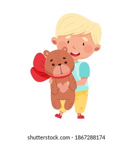 Flushed Boy Character with Blonde Hair Holding Bear Toy with Bow Vector Illustration