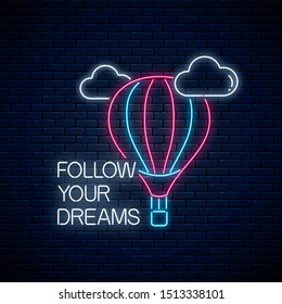 Follow your dreams - glowing neon inscription phrase with hot air balloon sign on dark brick wall background. Motivation quote in neon style. Vector illustration.