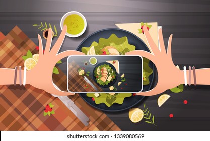 food blogger taking mobile photo of fresh vegetable salad with chicken and sauce in black bowl top angle view smartphone screen social network activity concept horizontal