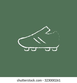 Football boot hand drawn in chalk on a blackboard vector white icon isolated on a green background.