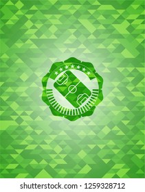 football field icon inside green emblem with triangle mosaic background