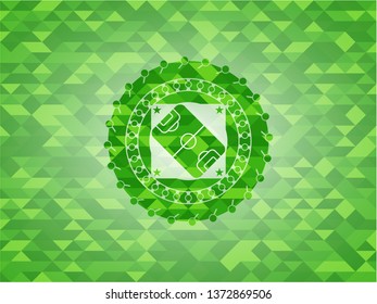 football field icon inside green emblem with triangle mosaic background