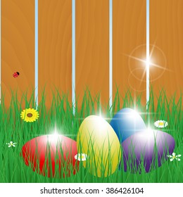 Four Easter eggs in the grass with fence 