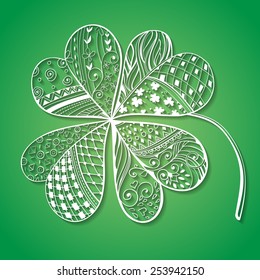 Four leaf, decorative white paper clover filled with hand- drawn floral and geometrical patterns on gradient green background. St. Patrick's day card