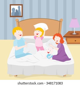 Four members of a family pillow fighting on a bed.
