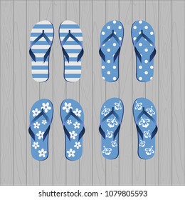Four pair of different flip flops - blue white colors on grey wooden background