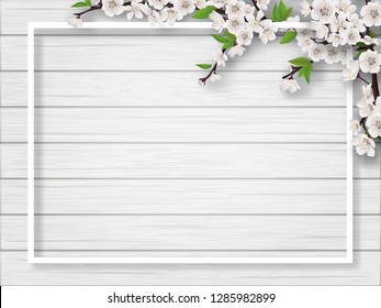 Frame with spring blossoming cherry branches on a white wooden background. Blank for advertising flyer or invitation card.