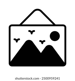 A framed landscape image with mountains, birds, and the sun hanging on a wall