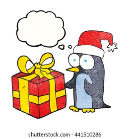freehand drawn thought bubble textured cartoon christmas penguin with present