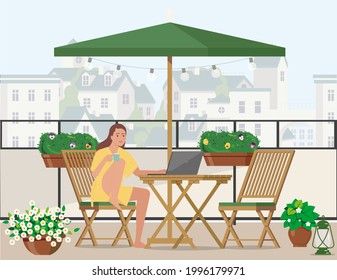 Freelancer-Mädchen arbeitet auf einem Laptop auf dem Balkon mit Blick auf die Stadt.