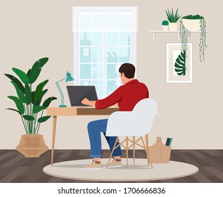 A freelancer man works behind a laptop. Home office workplace.