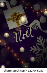 French text Joyeux Noel. Christmas background composition of decorative elements. Top view of gift box, decoration string lights garlands, balls and snowflakes. Greeting card, banner, web poster.