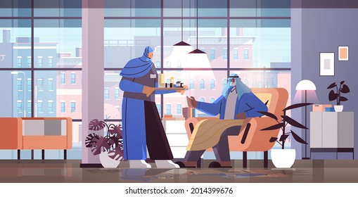 friendly arab nurse or volunteer bringing pills to arabic elderly man patient home care services healthcare