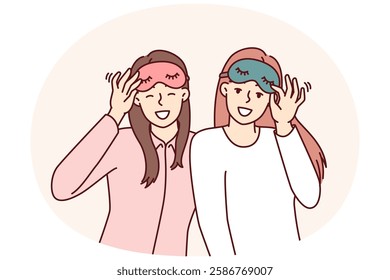 Friendly girls in pajamas with sleep masks are preparing to relax in comfortable bedroom with soft bed. Happy women use eye masks to protect themselves from sunlight during daytime naps or siestas