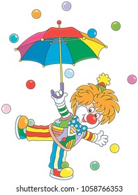 Friendly smiling circus clown dancing under a colorful umbrella in rain of color balls