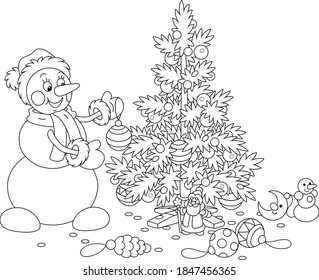 Friendly smiling snowman with a warm hat, a scarf and mittens decorating a prickly Christmas tree with balls, garlands and toys, black and white outline vector cartoon illustration